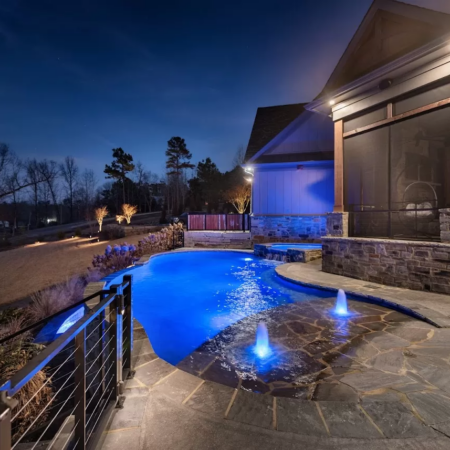 a small free form pool at night with purple lighting